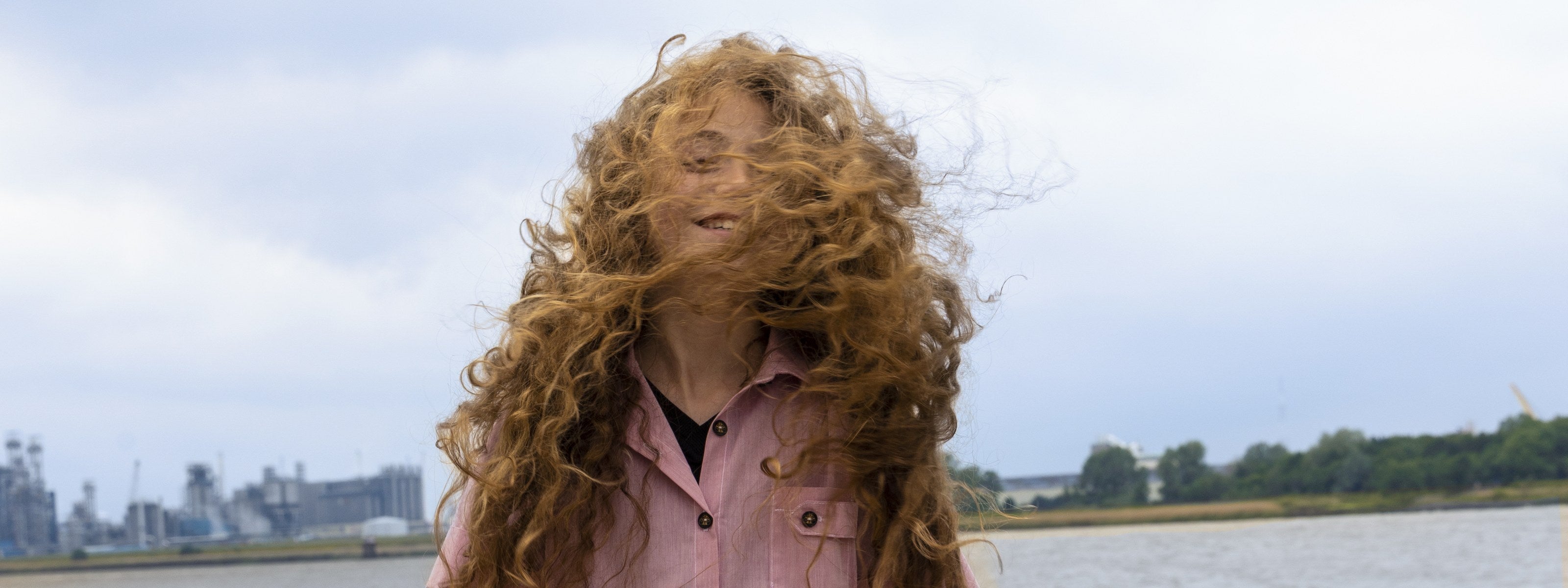 Girl in a pink hand-painted organic cotton dress on a windy beach — The Vacation Edit by Infantium Victoria